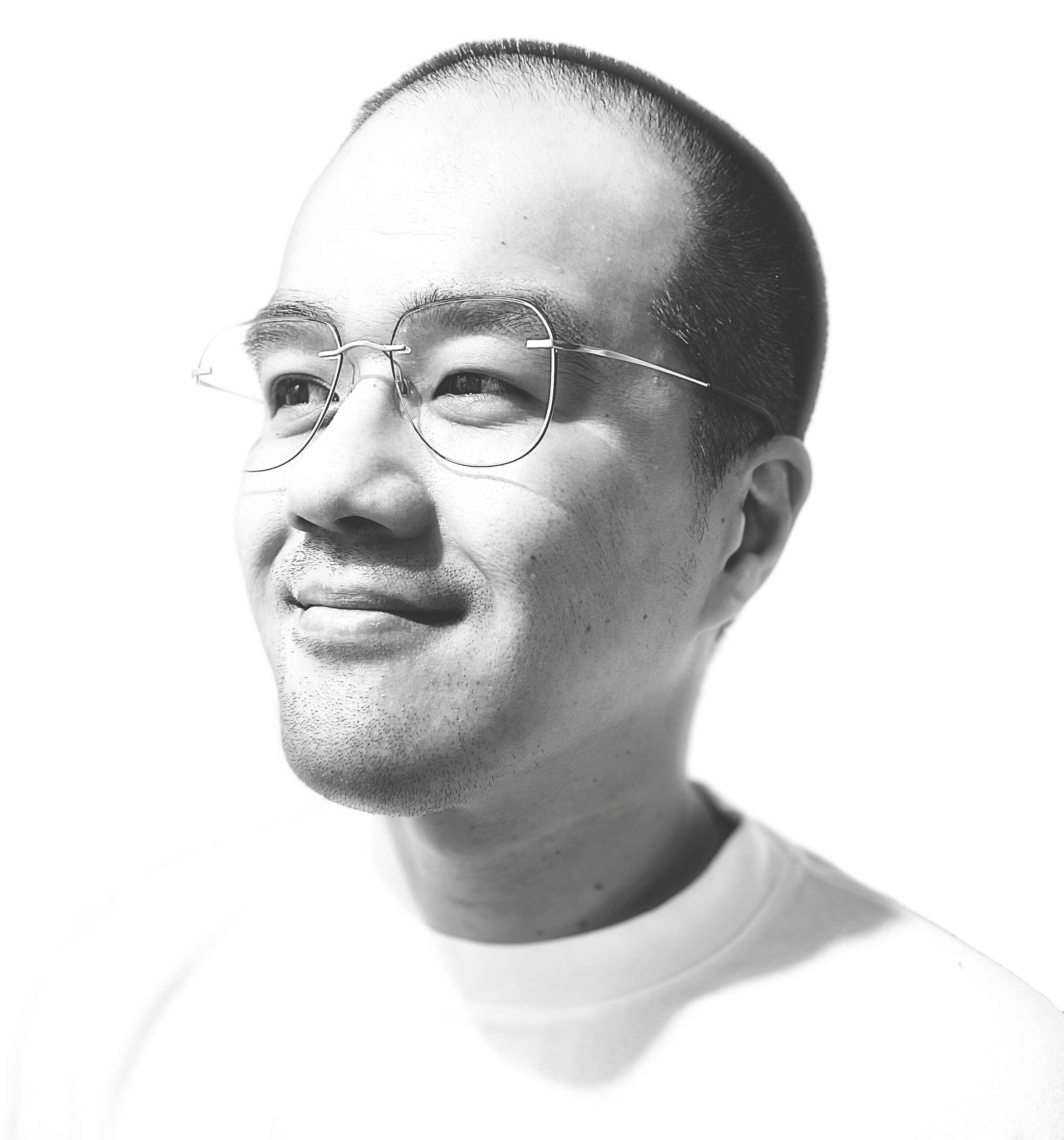 Alvis Ng, in a white T-shirt, looks up and to the left